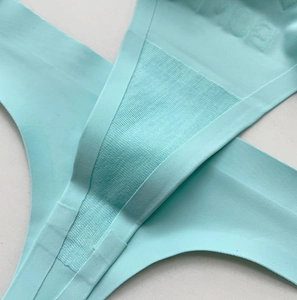Macro detail of seamless mint green thong with breathable mesh gusset and fine texture
