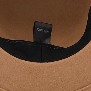 Gros plan de l'intérieur d'un chapeau en laine camel avec étiquette 100% laine