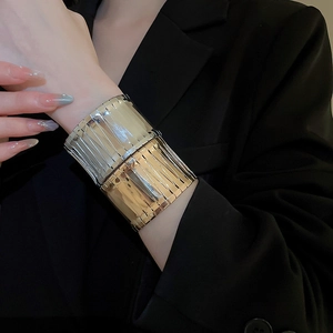 Macro detail of irregular two-tone gold and silver metal cuff bracelet with vertical texture