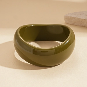 Detail view of a wide dark green acrylic resin bangle with a glossy marbled finish