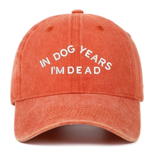 Détail de la broderie blanche sur une casquette en coton délavé de couleur rouge brique