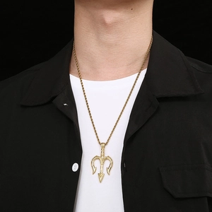 Détail d'un pendentif trident doré sur une chaîne torsadée porté par un mannequin