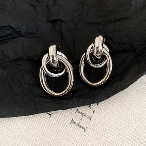 Macro shot of silver geometric linked earrings on black textured paper backdrop