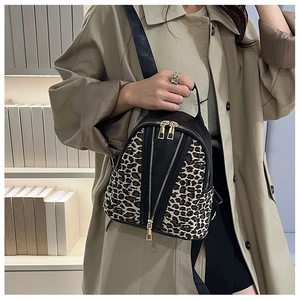 Detail of leopard print mini backpack featuring black leather trim and dual gold zippers