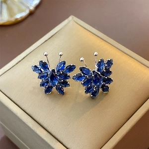 Macro view of blue butterfly stud earrings with marquise-cut stones on a jewelry box
