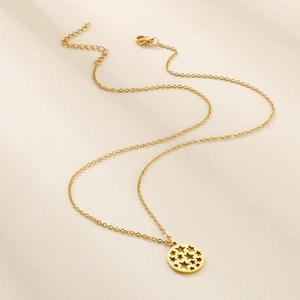 Detail of gold chain necklace with a circular pendant featuring hollow star patterns
