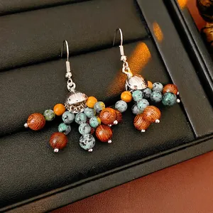 Bohemian dangle earrings with wooden beads and turquoise stones on a black leather tray