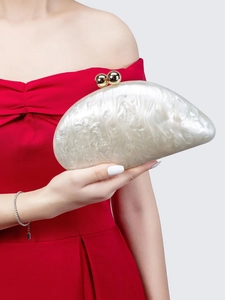 Detail of elegant white pearlescent acrylic crescent clutch bag with gold ball clasp