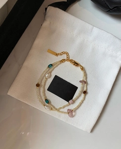 Detail of bohemian double-layer pearl bracelet with gold plating on white fabric bag
