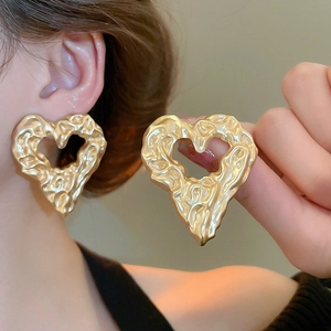 Detailed close-up of golden irregular lava texture heart earrings with matte finish