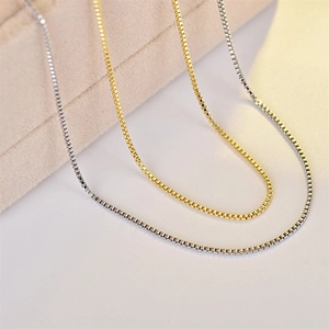 Close-up of minimalist gold and silver box chains with polished metallic luster