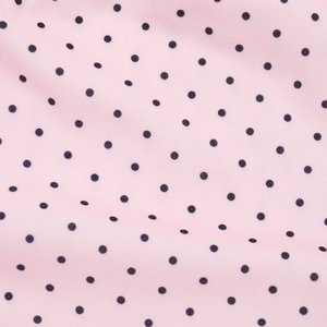Detailed close-up of pink fabric with black polka dots showing soft textile texture