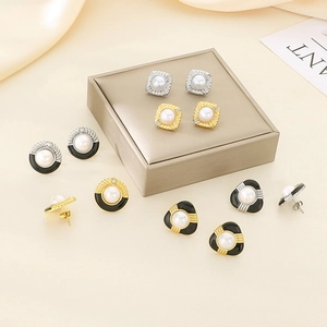 Vue macro de boucles d'oreilles géométriques avec perles blanches et détails en zircone
