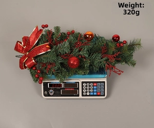 Christmas teardrop swag with red balls and bow on a scale showing 320g weight