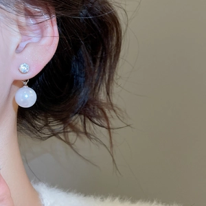 Close-up of elegant silver stud earrings with sparkling zircon and round white pearl