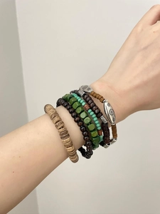 Details von mehrlagigen Boho-Armbändern mit Holzperlen und einem gravierten Sonnentotem