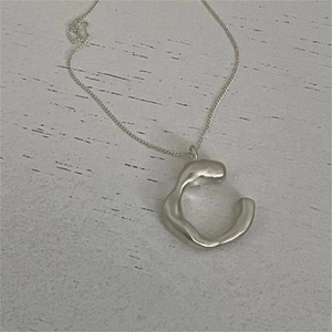 Minimalist 925 sterling silver necklace with irregular C-shaped pendant on a white background