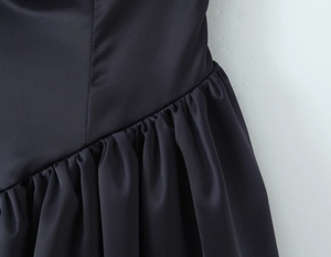 Vue détaillée du tissu en satin foncé montrant les plis complexes à la taille