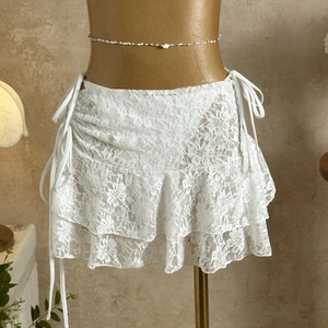 Detailed view of white floral lace ruffle skirt with side tie and bead waist chain