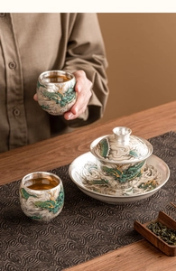 Close-up of elegant silver tea set featuring intricate dragon patterns and Gaiwan