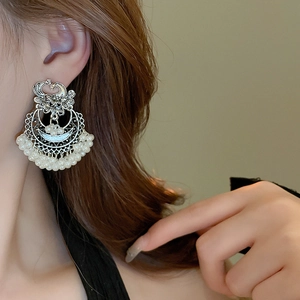 Detailed view of ethnic peacock earrings featuring hollow carvings and pearl decorations