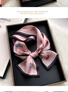 Pink silk scarf with horse patterns in a luxury black gift box on white fur background
