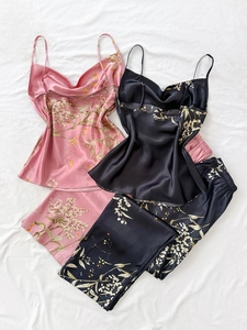 Detailed flat lay of floral print satin pajama sets in pink and black silk-like fabric