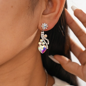 Gros plan de boucles d'oreilles fleur et cœur en cristal portées avec strass scintillants