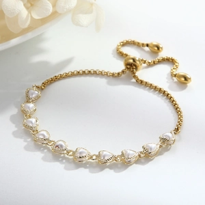 Close-up of heart-shaped pearl bracelet with adjustable gold chain and elegant white flowers