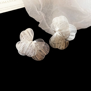 Détail macro de boucles d'oreilles fleurs ajourées en argent sur un fond minimaliste