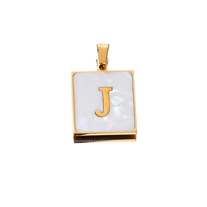 Macro view of square stainless steel pendant with white pearl shell and gold letter J