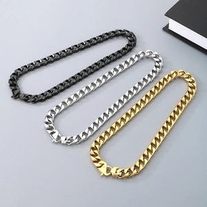 Flat lay of Cuban link necklaces in black, silver and gold finish on grey surface