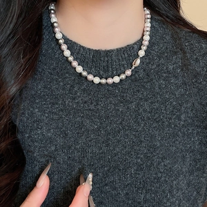 Detailed view of French-style necklace with white, grey, and lavender pearls on a model