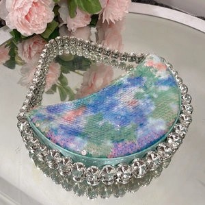 Close-up of macaron sequin crescent bag with crystal handle and satin details