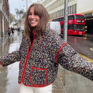 Short quilted cotton jacket with floral berry print and red piping on navy base fabric
