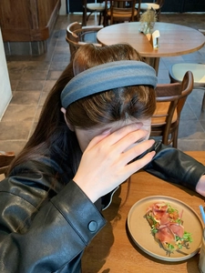 Detailed texture of dark grey fabric wide headband shown in a real-life cafe setting