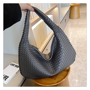 Detail showing high-quality hand-woven texture on a dark grey leather hobo shoulder bag