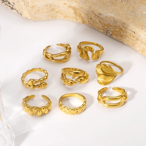 Set of 8 gold geometric hollow rings with varied vintage designs on white surface