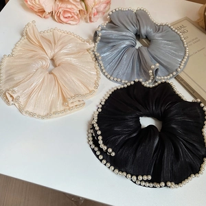 Detailed view of champagne and blue mesh hair scrunchies with white pearls accents