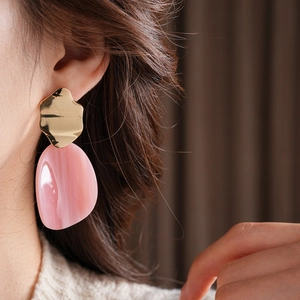 Gros plan de boucles d'oreilles en acrylique rose de forme ovale portées par un mannequin