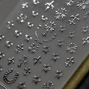Macro shot of silver 3D nail art stickers with cross and star patterns on backing