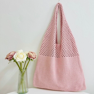 Detail of pink hand-crocheted tote bag with intricate hollow knit textures and soft cotton