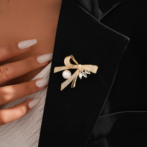 Macro shot of bow brooch with 14k gold plating, pavé zircons and a large white pearl