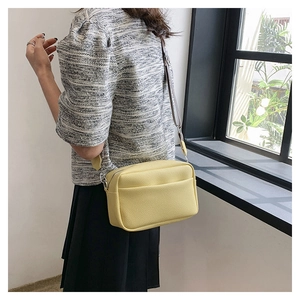 Close-up of bright yellow camera bag with litchi texture on a female model