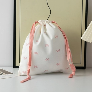 Detail of white cotton drawstring pouch with pink bow prints and woven cords