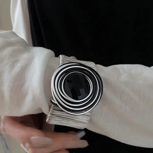Detail of a chunky silver multi-wire wrap bracelet with bold black and white resin circles