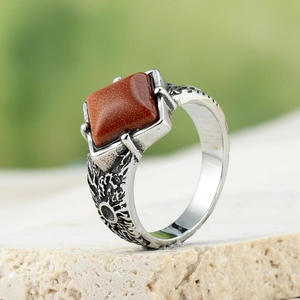 Macro detail of retro stainless steel ring with red sandstone inlay and rustic texture