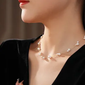 Collier double rangée en chaîne dorée avec perles blanches sur le cou d'un mannequin