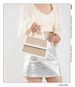 Chic beige and white color-block handbag styled with metallic skirt and knit sweater