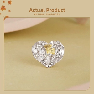 Détail du charm cœur en argent s925 avec feuille de ginkgo dorée et zircons blancs